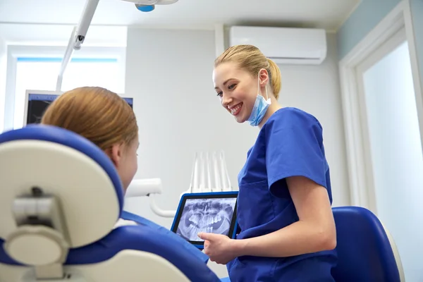 Dentista que muestra rayos X en el comprimido pc a la niña paciente —  Fotos de Stock