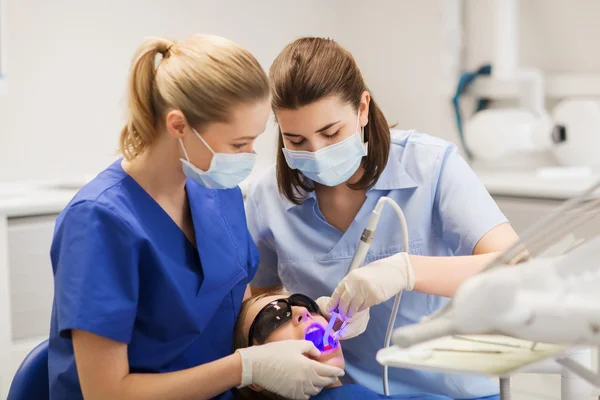 Dentistas mujeres que tratan los dientes de niña paciente —  Fotos de Stock