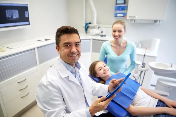 Стоматолог з планшетним ПК, дівчина-пацієнт і мати — стокове фото