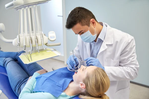 Чоловічий стоматолог у масці для перевірки жіночих зубів пацієнта — стокове фото