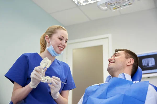 Dentista feliz mostrando layout da mandíbula para paciente masculino — Fotografia de Stock