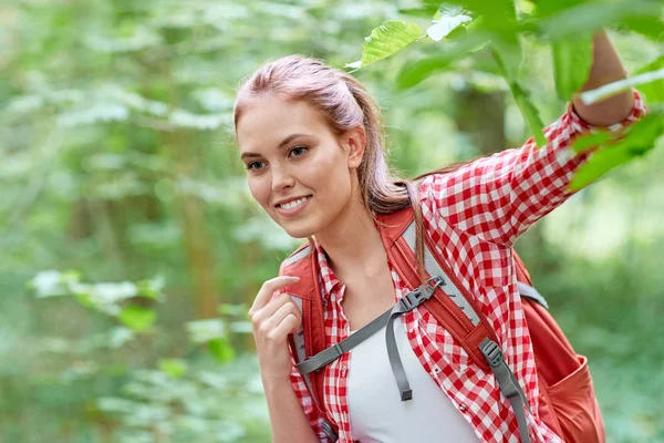 Uśmiechnięta młoda kobieta z plecak wędrówki w lesie — Zdjęcie stockowe