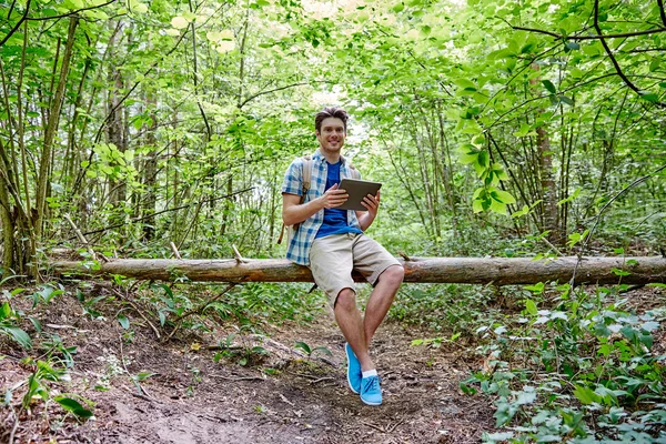 Gelukkig man met rugzak en tablet pc in bos — Stockfoto