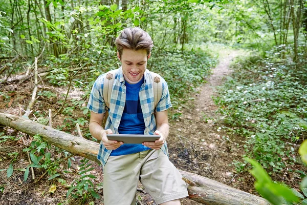 Gelukkig man met rugzak en tablet pc in bos — Stockfoto