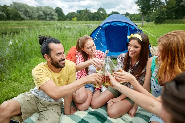 Happy friends with tent and drinks at campsite — Stock Photo, Image