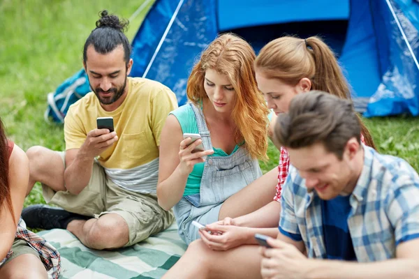 Друзья со смартфоном и палаткой в кемпинге — стоковое фото