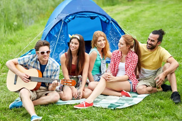 Happy friends with drinks and guitar at camping — Stock Photo, Image