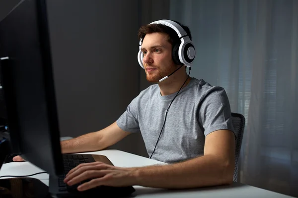 Homme dans casque jouant jeu vidéo d'ordinateur à la maison — Photo