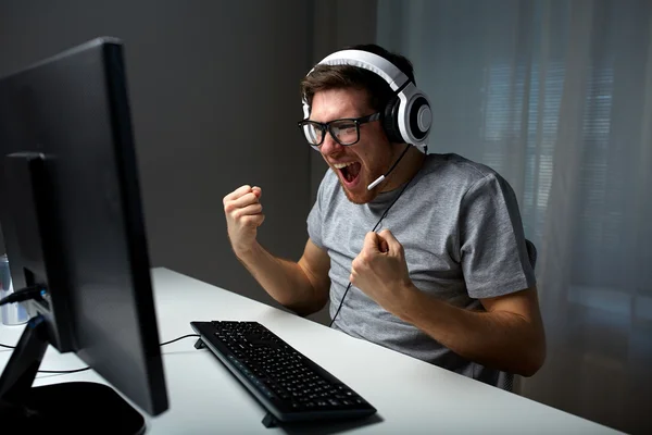 Hombre en auriculares jugando videojuego de ordenador en casa —  Fotos de Stock