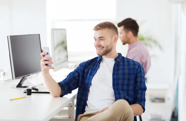 Щасливий творчий чоловік смс на мобільний телефон в офісі — стокове фото
