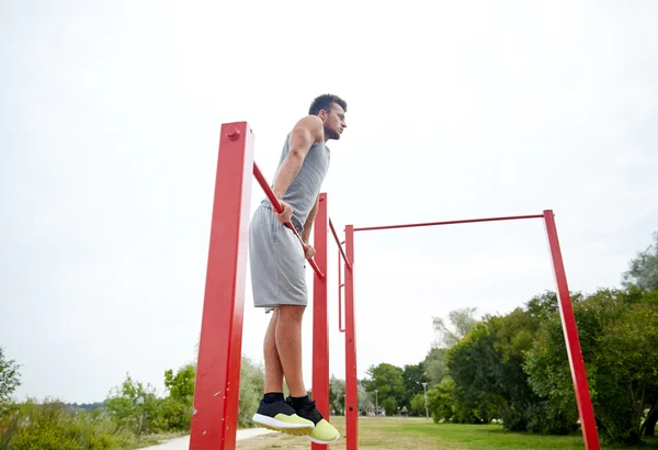 Jongeman die buiten op de horizontale balk traint — Stockfoto