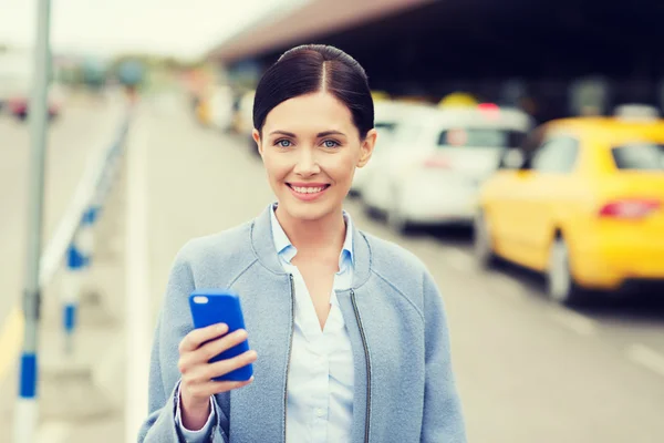 Smiling woman with smartphone over taxi in city — Stock Photo, Image