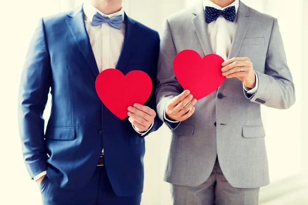 Close up of male gay couple holding red hearts — Stock Photo, Image