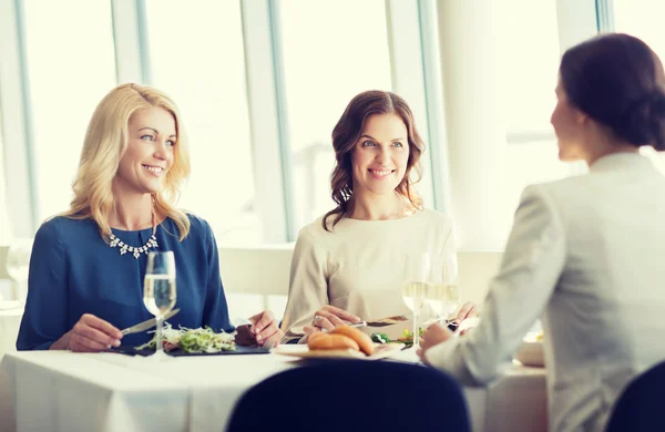 Gelukkig vrouwen eten en praten in restaurant — Stockfoto