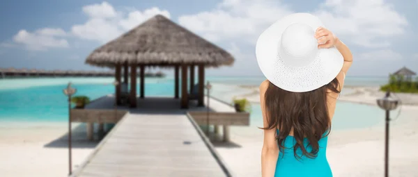 Женщина в купальнике и шляпе со спины на пляже — стоковое фото