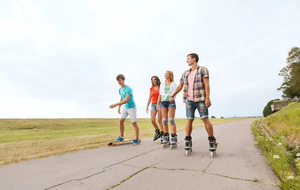 Adolescenti felici con pattini a rotelle e longboard — Foto Stock