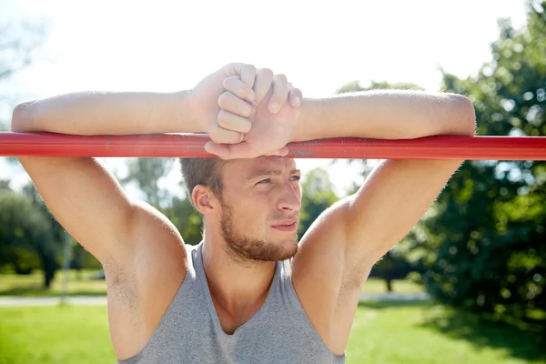 Young man exercising on horizontal bar outdoors — Stock Photo, Image