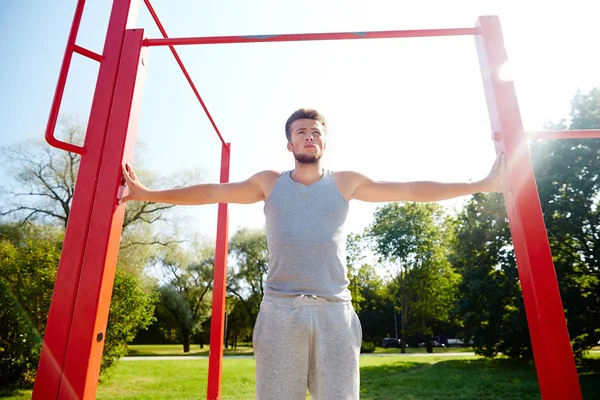 Jongeman die buiten op de horizontale balk traint — Stockfoto