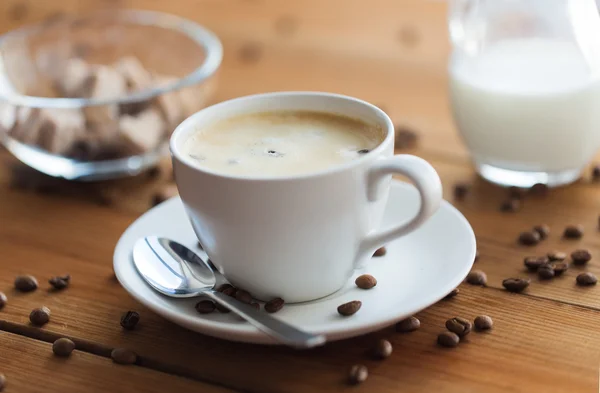 Fechar xícara de café e grãos na mesa de madeira — Fotografia de Stock