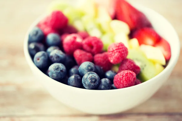 Закрытие фруктов и ягод в миске на столе — стоковое фото