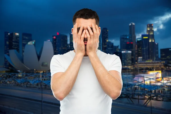 Homme en t-shirt blanc couvrant son visage avec des mains — Photo