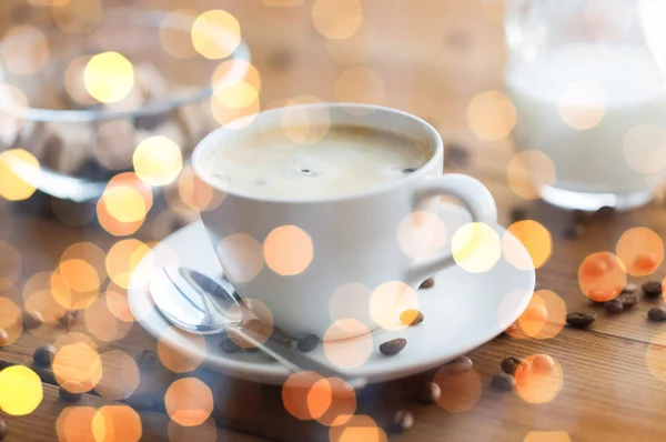 Fechar xícara de café e grãos na mesa de madeira — Fotografia de Stock