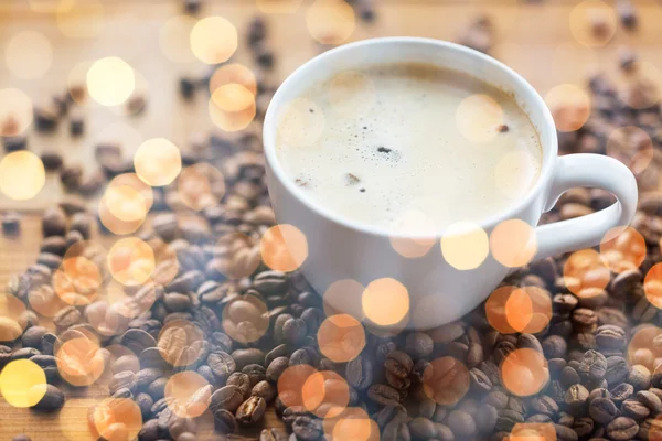 Cerrar taza de café y granos en la mesa de madera — Foto de Stock