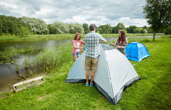 Grupo de amigos sonrientes instalando carpa al aire libre — Foto de Stock