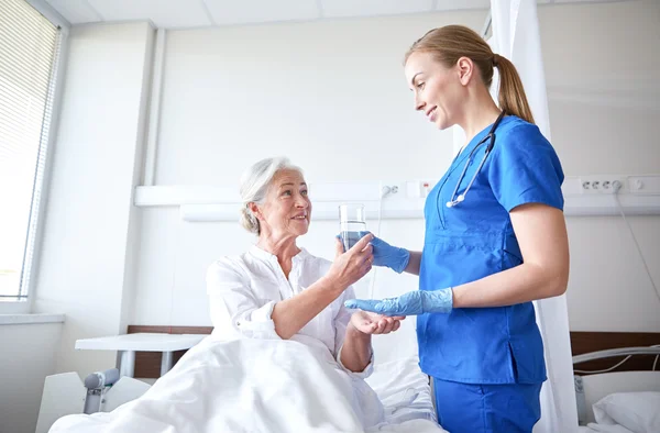 Медсестра дає ліки старшій жінці в лікарні — стокове фото