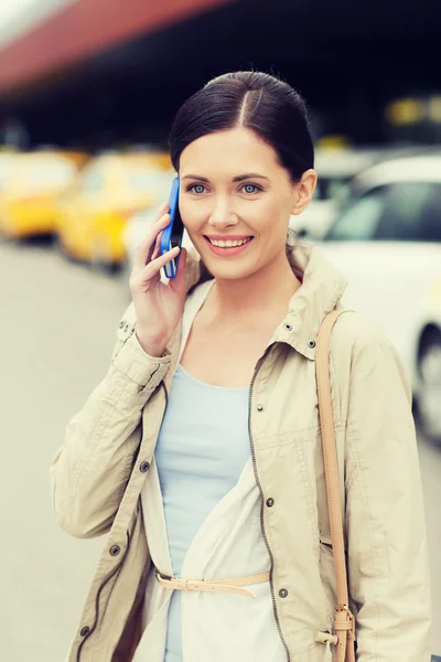 Lächelnde Frau mit Smartphone über Taxi in der Stadt — Stockfoto