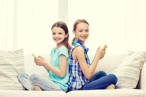 Meninas felizes com smartphones sentados no sofá — Fotografia de Stock