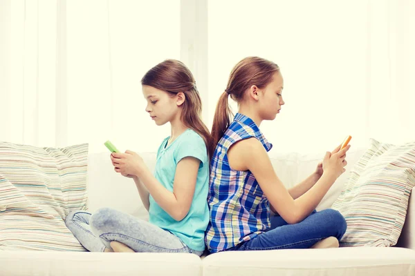 Meninas com smartphones sentados no sofá em casa — Fotografia de Stock