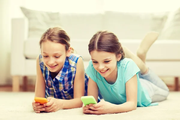 Chicas felices con teléfonos inteligentes tumbados en el suelo — Foto de Stock