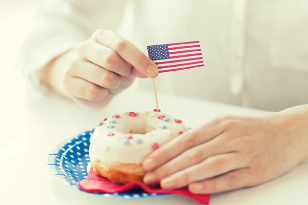 Weibliche Hände dekorieren Donut mit amerikanischer Flagge — Stockfoto