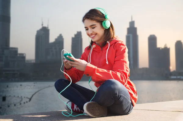 Szczęśliwa młoda kobieta z smartphone i słuchawki — Zdjęcie stockowe