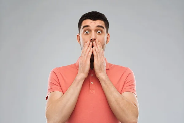 Scared man in polo t-shirt over gray background — Stock Photo, Image