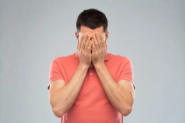 Man in t-shirt covering his face with hands — Stock Photo, Image