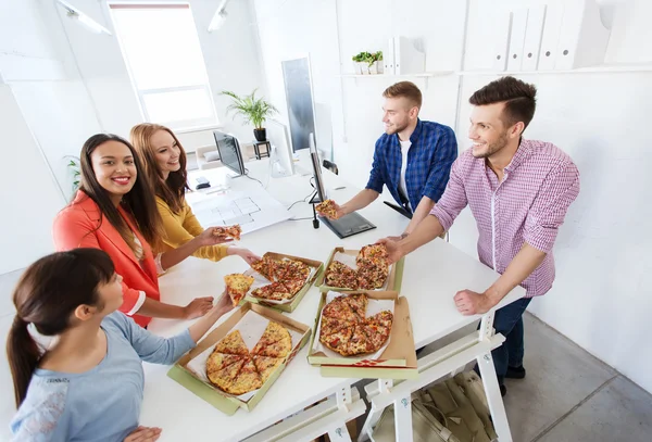 Equipe de negócios feliz comer pizza no escritório — Fotografia de Stock