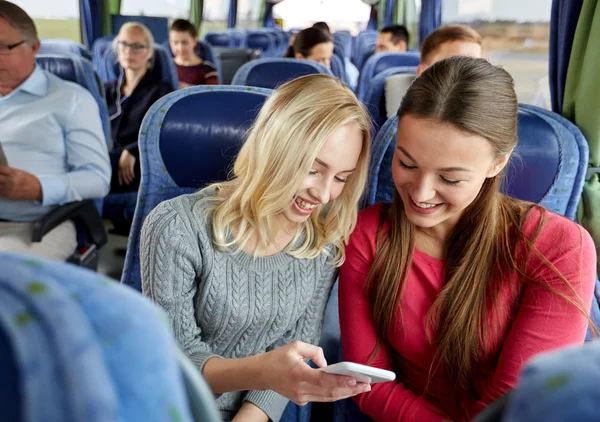 Šťastné mladé ženy v cestovním autobuse s chytrým telefonem — Stock fotografie