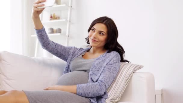 Gravid kvinna med selfy av smartphone hemma — Stockvideo