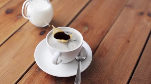 Azúcar cayendo en la taza de café en la mesa de madera — Vídeo de stock