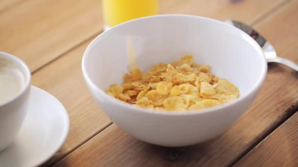 Cornflakes gieten om kom op houten tafel — Stockvideo