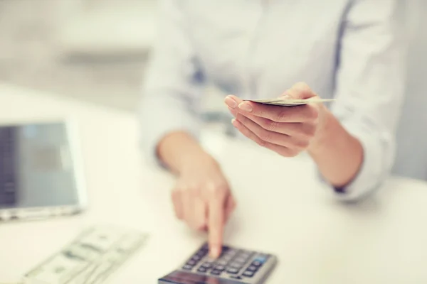 Close up of woman counting money with calculator — Stock Photo, Image