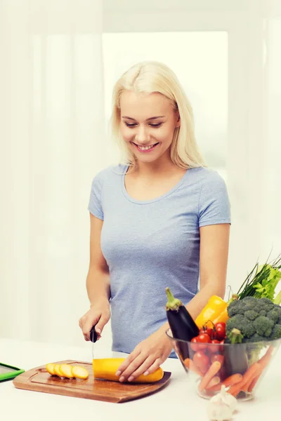 Souriant jeune femme hacher des légumes à la maison — Photo