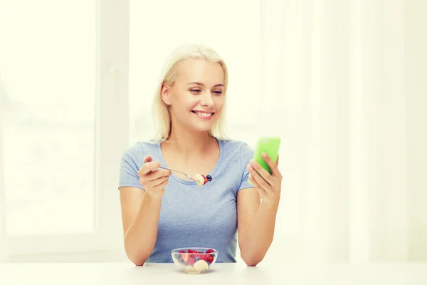 Frau mit Smartphone isst Obst zu Hause — Stockfoto