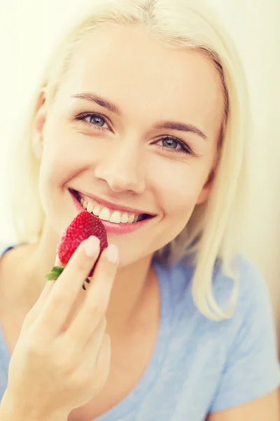Lycklig kvinna äta jordgubbar hemma — Stockfoto