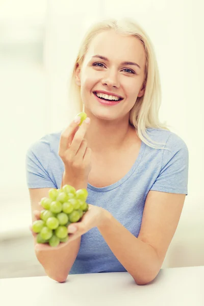 Mulher feliz comendo uvas em casa — Fotografia de Stock