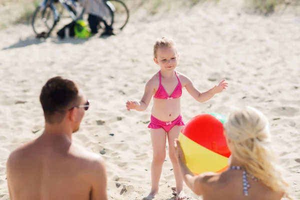 Famille heureuse jouant avec le ballon gonflable sur la plage — Photo