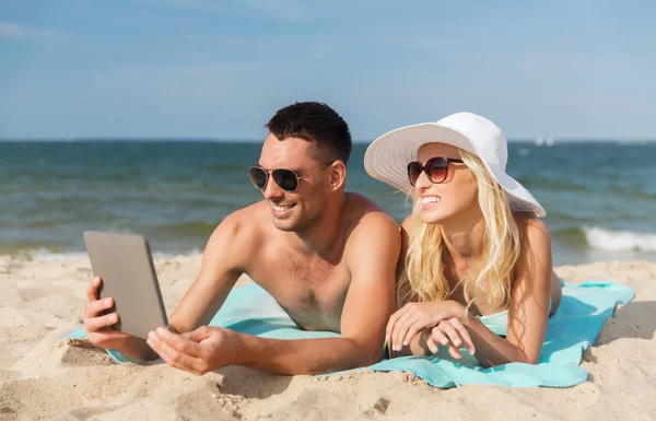 Feliz pareja con tableta pc tomar el sol en la playa — Foto de Stock