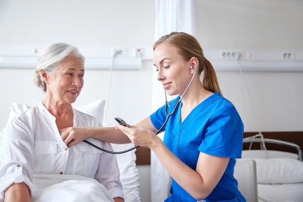 Infirmière avec stéthoscope et femme âgée à la clinique — Photo